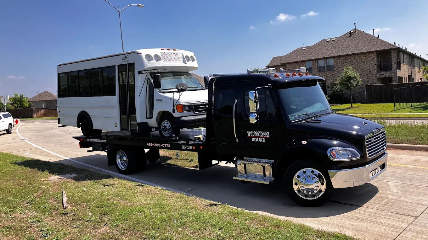 Towing Squad flatbed carrying a white shuttle bus