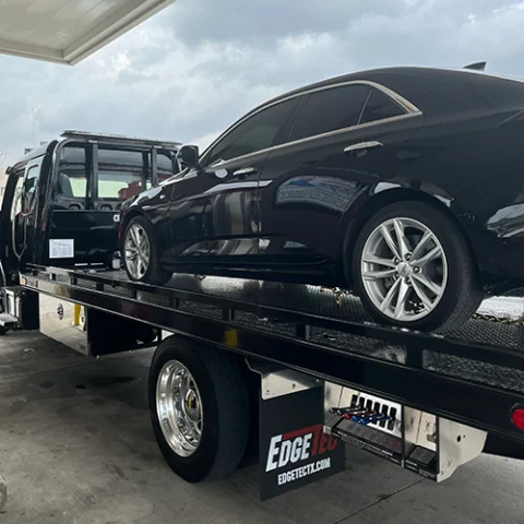 Black Cadillac sedan on a Towing Squad flatbed