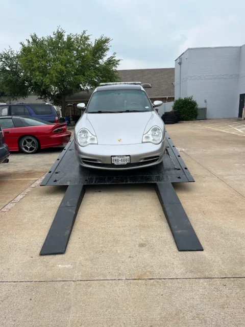 Silver Porsche 911 loaded on a flatbed with ramps