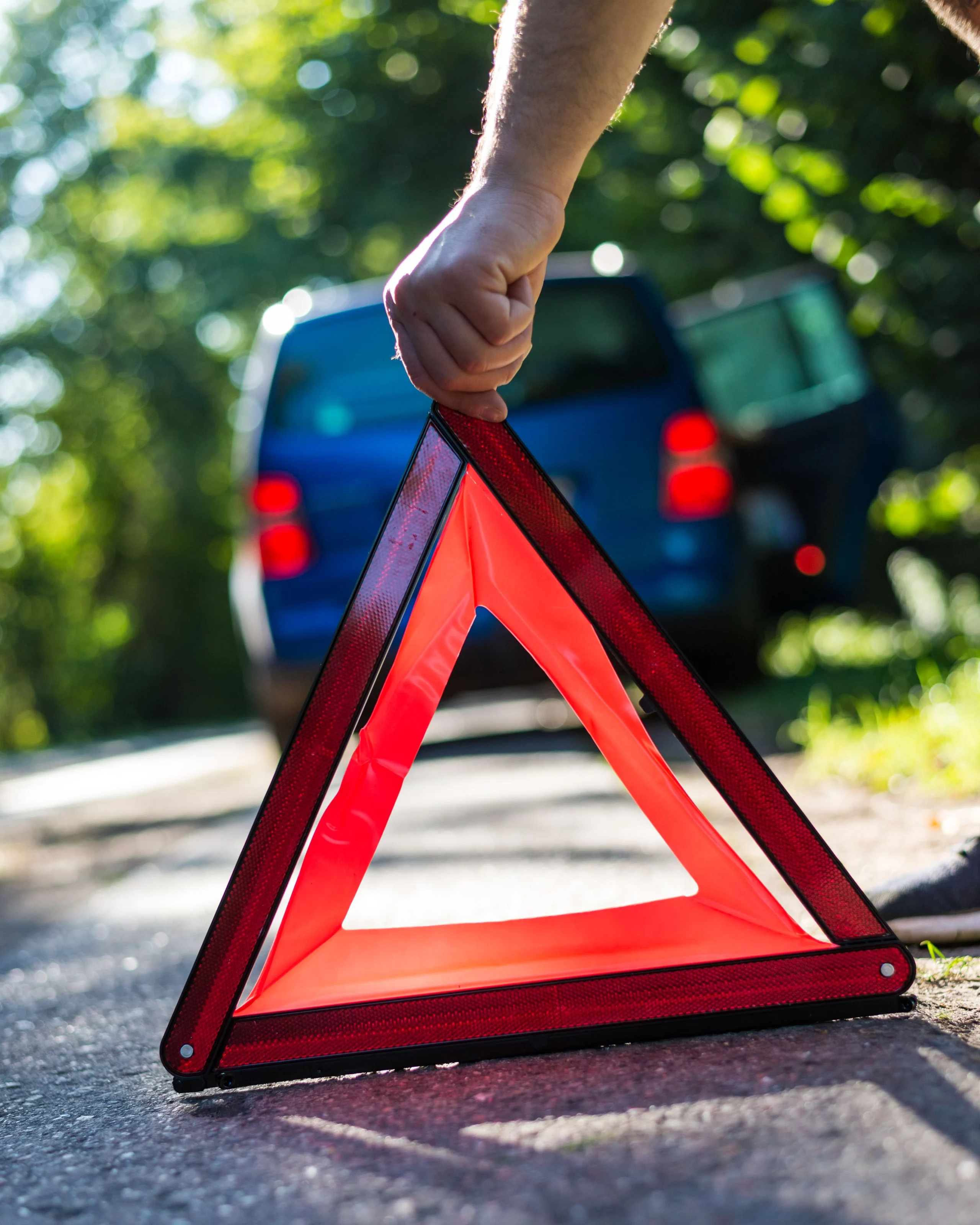 Driver placing an emergency warning triangle next to a stopped car